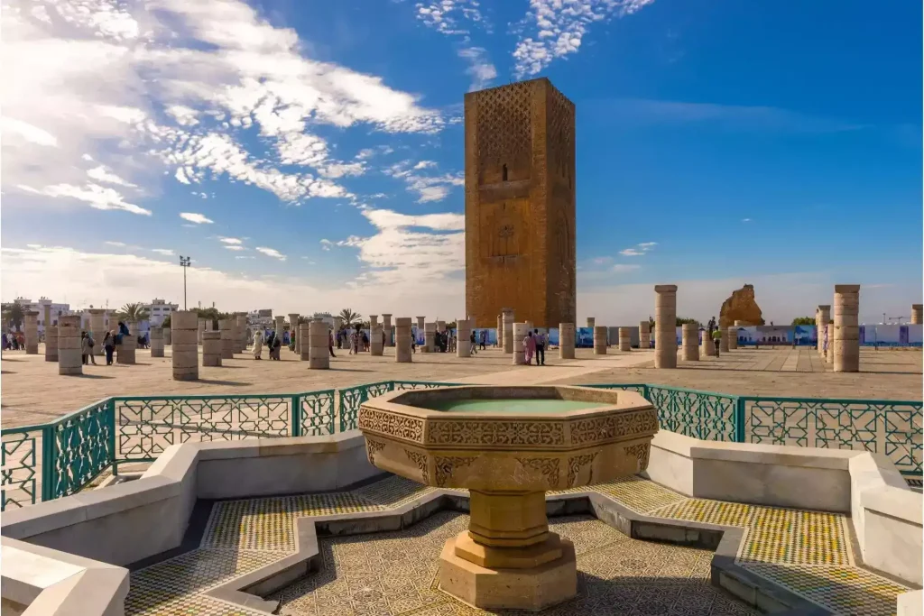 Hassan Tower in Rabat with visitors and an ornate fountain in front of it
