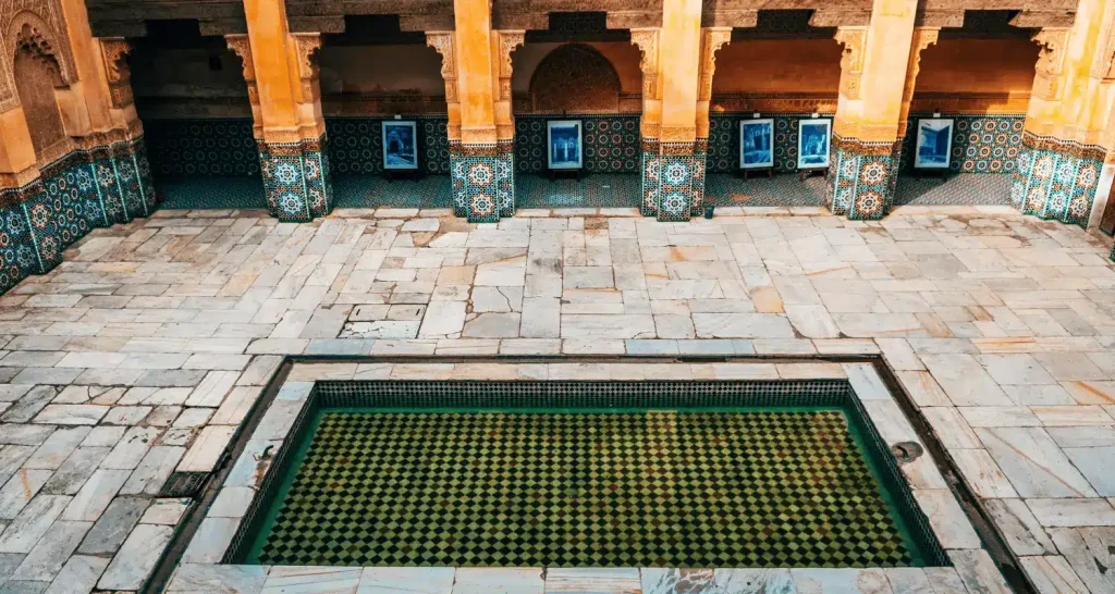 Innenhof einer traditionellen marokkanischen Madrasa mit zelligen Fliesen und einem zentralen Pool.