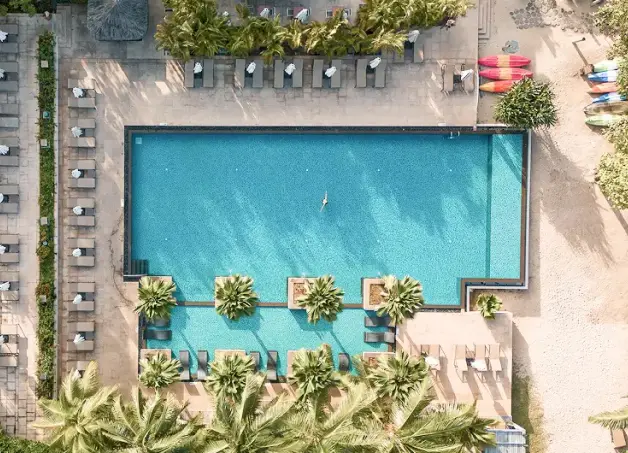 A stunning aerial view of the outdoor pool at STORY Hotels & Resorts in Rabat, Morocco, showcasing the luxurious setting with palm trees and lounge chairs. This 5-star hotel in Rabat offers an exceptional place to unwind and enjoy the Moroccan sun.