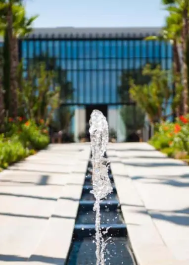 Wasserfontäne entlang eines begrünten Weges, der zum modernen Eingang des STORY Rabat, einem der führenden Hotels in Rabat, führt.
