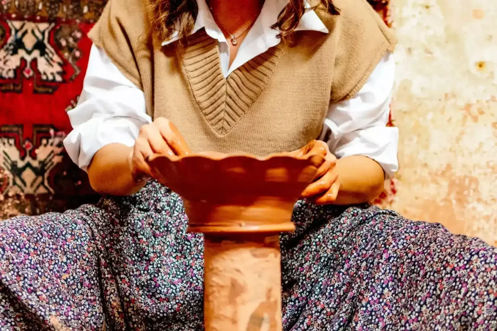 Young woman makes a clay pot on a pottery wheel