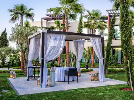 Un dîner romantique en plein air à STORY Rabat, avec un gazebo aux rideaux flottants, des lanternes et de la verdure luxuriante, créant une atmosphère parfaite pour un dîner privé et luxueux au cœur de Rabat, au Maroc.