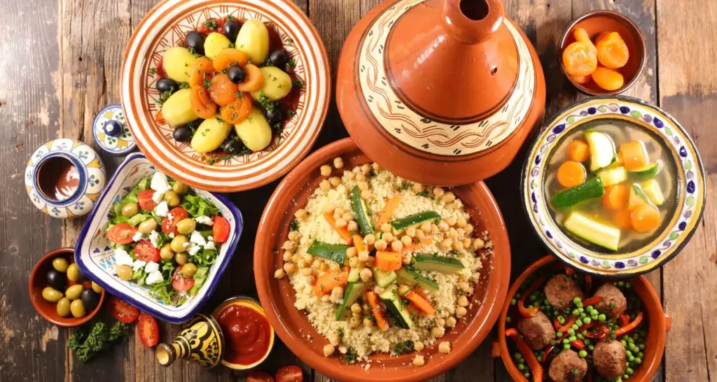 Marokkanisches Gericht mit Couscous, Gemüse und Tajine, serviert auf einem Holztisch