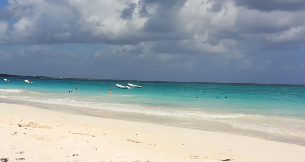 Die friedliche Küste des Plage des Nations mit türkisfarbenem Wasser und sanften Wellen unter bewölktem Himmel