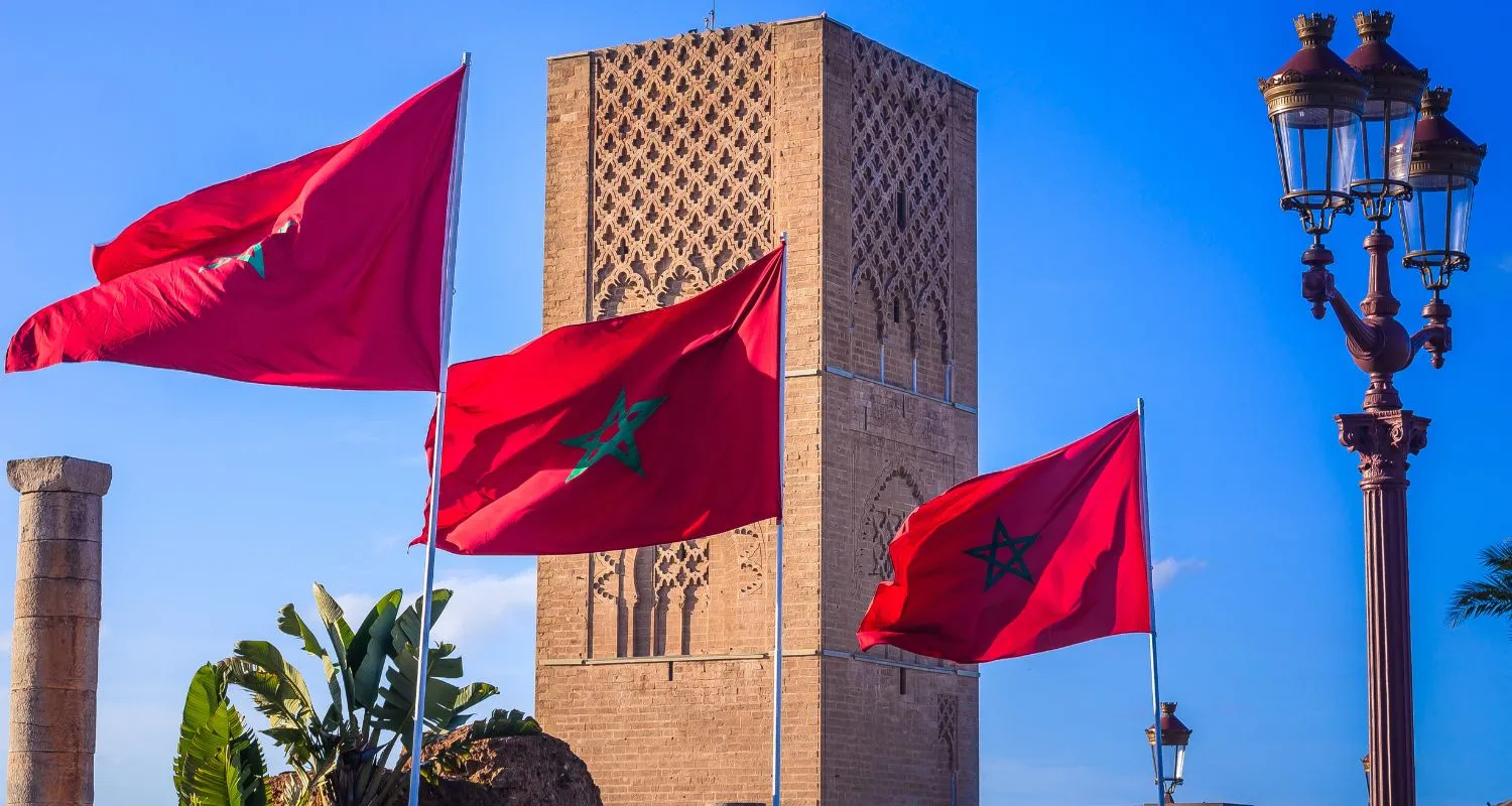 Moroccan flags flying near a historic minaret in Rabat during national celebrations