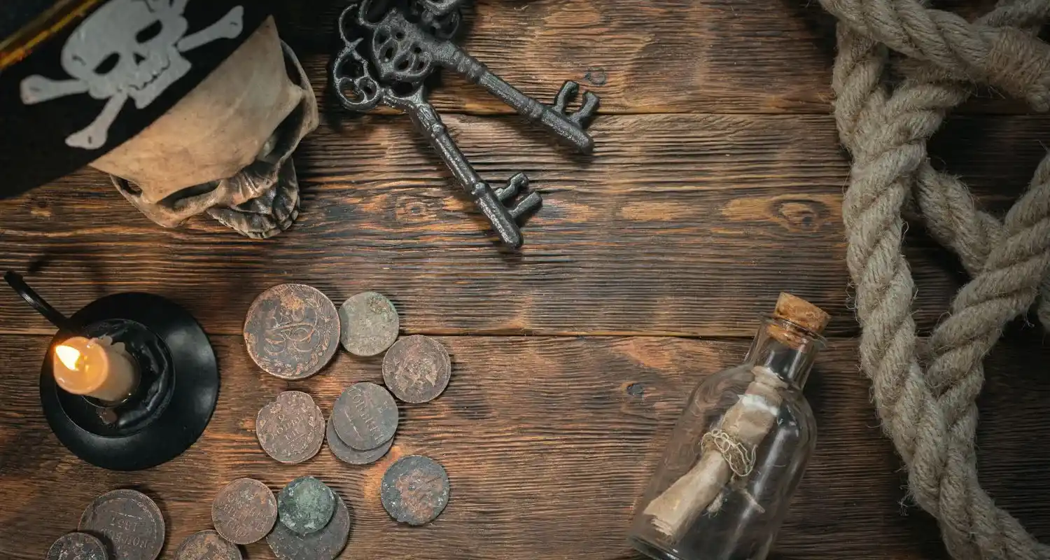 Corsair-era props on weathered wood — a skull, old iron keys, copper coins, a lit candle, coiled rope and a message in a bottle, evoking Salé's pirate past